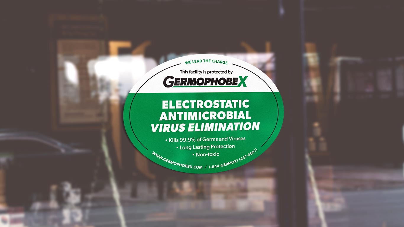 A green and white sticker that reads "Electrostatic antimicrobial virus elimination" on the window of a store that uses their cleaning services