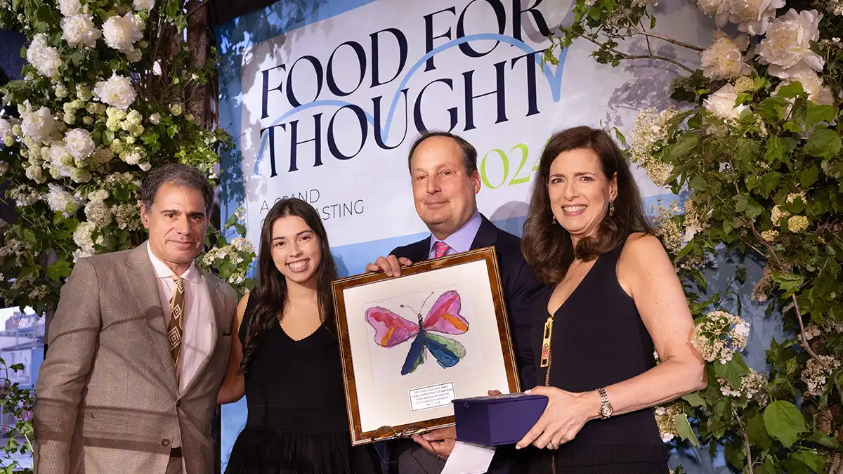 A speaker at the Food for Thought Gala standing in front of a branded backdrop.